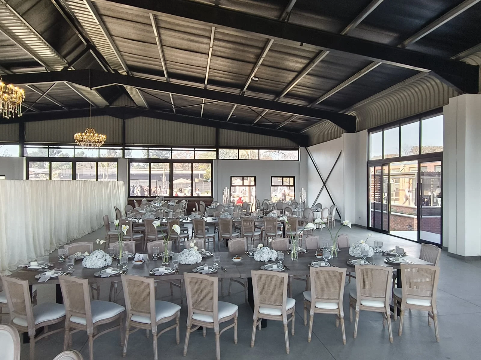 Main hall set for an event, with chandeliers and views across the garden